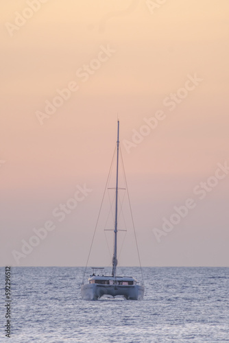 Sailboat on the ocean near the beach at sunset. © Elena Krivorotova