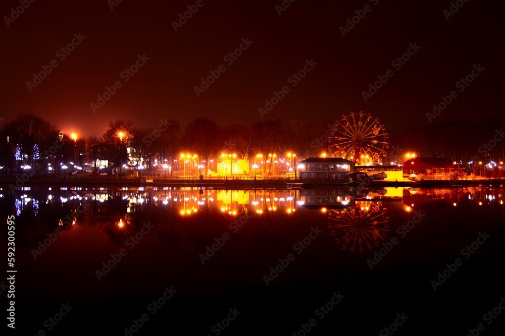 Carousels wheel and city and reflection at night in city