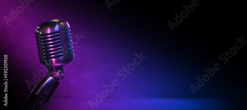 Vintage vocal microphone in the dark with pink and blue lighting and copy space for podcast banner background or jazz club, comedy club or music content