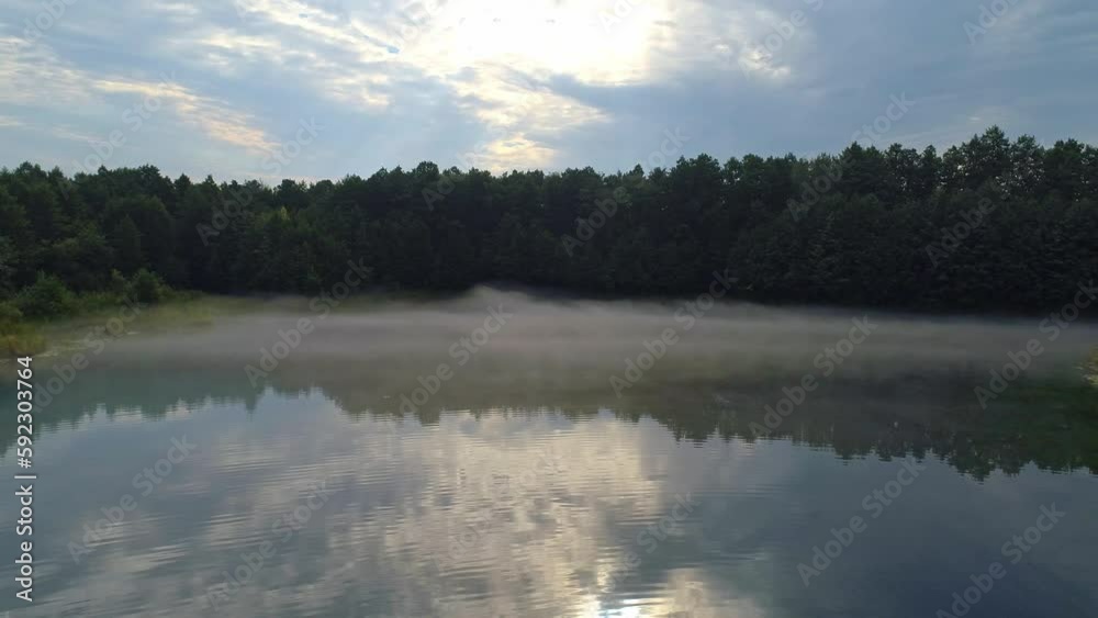 Early morning mist floating over calm water, lake. Aerial view flying slowly and low over a lake in fog. Early morning mist floating over calm water, lake. Aerial view flying slowly and low over a lake in fog.