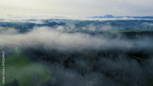 Impressive drone hyper-lapse shot of the foggy Upper Austrian alpine foothills with Traunstein mountain in the background. Camera moves backwards through the patches of fog.