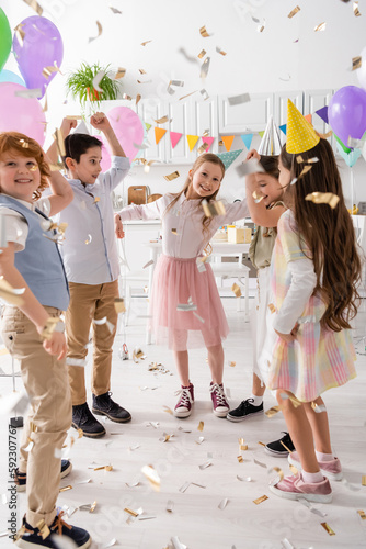 Canvastavla happy kids in party caps dancing under falling confetti during birthday celebration at home