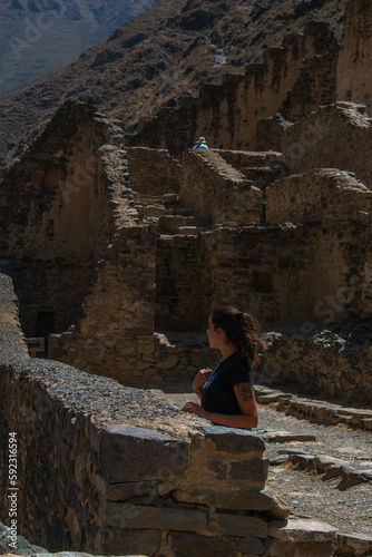 Young woman in profile at the archaeological site of Ollantaytambo with view of the ruins, Peru