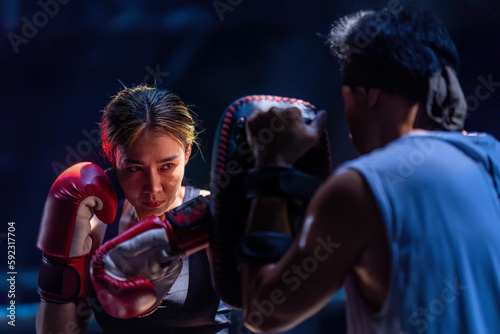 Female kickboxing training with male trainer gives self-defense classes to female fighter at GYM. Asian beautiful young woman exercise with trainer at boxing gloves, uppercut short, boxing, training © somchairakin