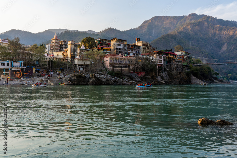Beautiful River Ganga in Rishikesh surrounded by ashrames and temples building. Pure natural clean river water.