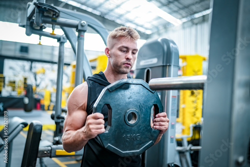 Male athlete exercising in the gym, lifting weights, pulling joints.