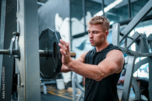 Male athlete exercising in the gym, lifting weights, pulling joints.