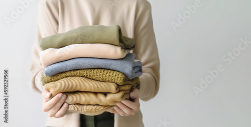 Woman's hand holding a stack of clothes. Clothes Donation, Renewable Concept.Preparing Garment at Home before Donate. generative ai