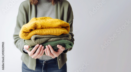 Woman's hand holding a stack of clothes. Clothes Donation, Renewable Concept.Preparing Garment at Home before Donate. Woman packs clothes for a donation or for moving. generative ai photo