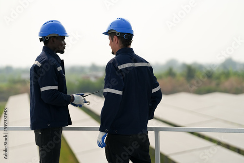 Electrician engineer with white helmet working at a photovoltaic farm, checking and maintenance equipment with instruments at industry solar power.