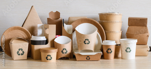 Lots of disposable paper containers and utensils with a recycling sign. Panorama. The concept of recycling and zero waste