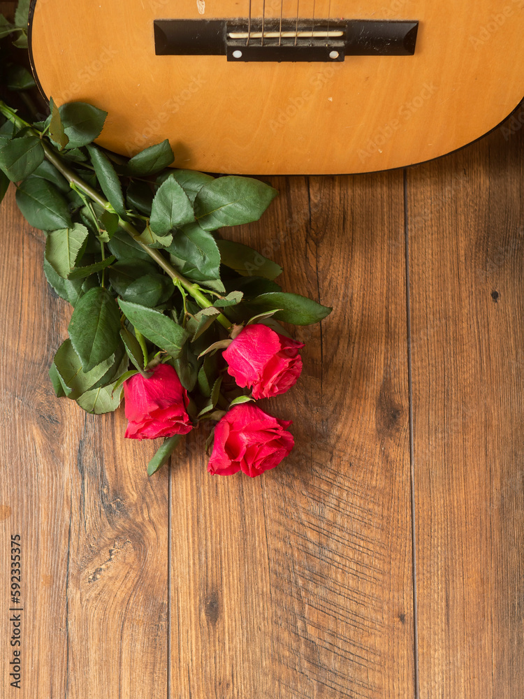 Classic acoustic guitar on a wooden floor and bouquet of red rosses. Expression of gratitude and love for great music performance. Romantic background. Classic acoustic guitar on a wooden floor and bouquet of red rosses. Expression of gratitude and love for great music performance. Romantic background.