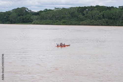 People canoeing kayaking on Amazon river with green jungle tree and sky at Puerto Maldonado Peru. photo