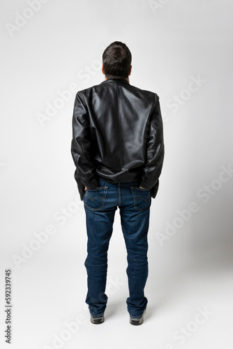 Man isolated on white background looks up and has his hands in the diestro pockets of his blue jeans.