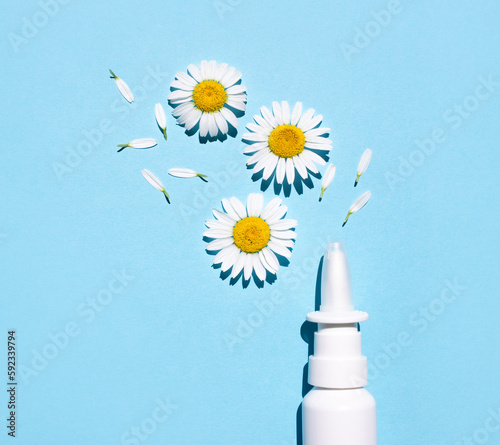 Nasal spray and natural chamomiles on a blue background. Treating seasonal allergies. Top view, place for text.