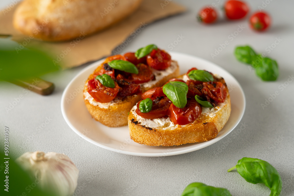 Bruschetta with Ricotto cheese and cherry Tomatoes, basil, garlic on a grey concrete background. Food. Food background. Close-up Bruschetta with Ricotto cheese and cherry Tomatoes, basil, garlic on a grey concrete background. Food. Food background. Close-up