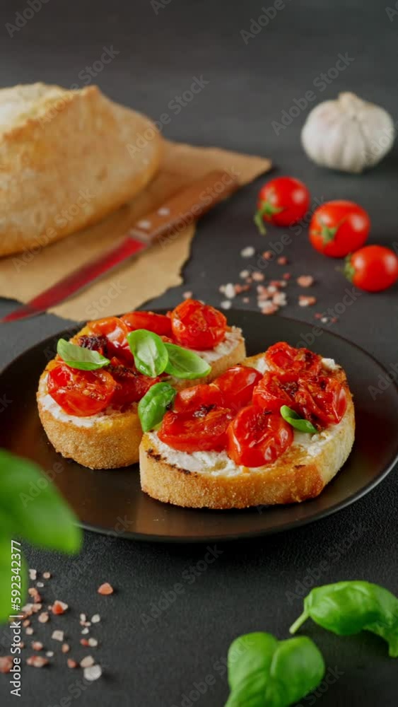 Bruschetta with Ricotto cheese and cherry Tomatoes, Basil, garlic on a black background. Food background. Vertical video Bruschetta with Ricotto cheese and cherry Tomatoes, Basil, garlic on a black background. Food background. Vertical video