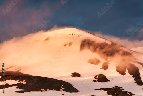 Sunset shining on Kerlingarfjoll volcanic mountain peak with snow covered on geothermal area during golden hour in Icelandic Highlands