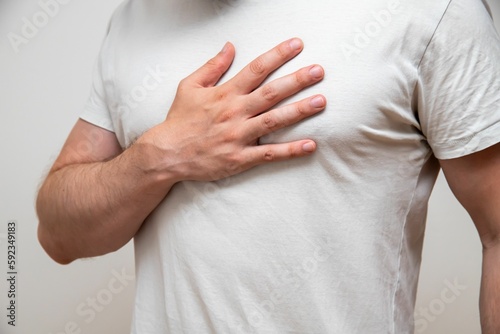 Closeup shot of a man with his hand on his chest indicating pain