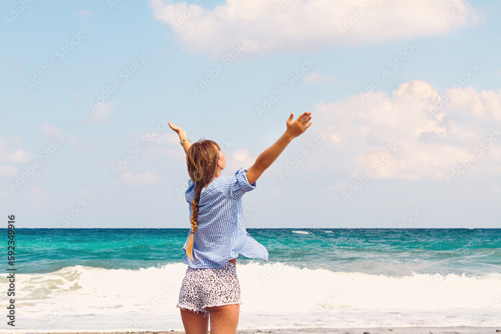 beautiful young woman on the ocean posing raising her hands up rear view. Vacation and travel beautiful young woman on the ocean posing raising her hands up rear view. Vacation and travel
