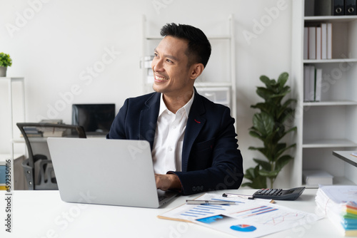 Happy Asian businessman working with laptop computer in the white modern office room. © PaeGAG