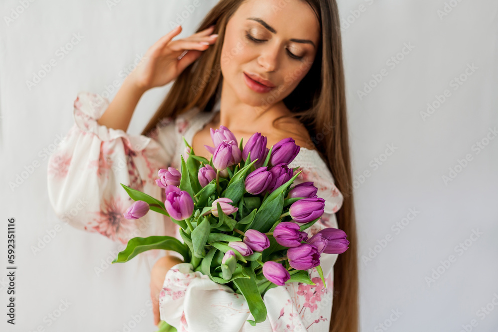 Portrait of sexy beautiful young woman with long hair. Model with a bouquet of lilac tulips on white. Spring. Holidays. Portrait of sexy beautiful young woman with long hair. Model with a bouquet of lilac tulips on white. Spring. Holidays.