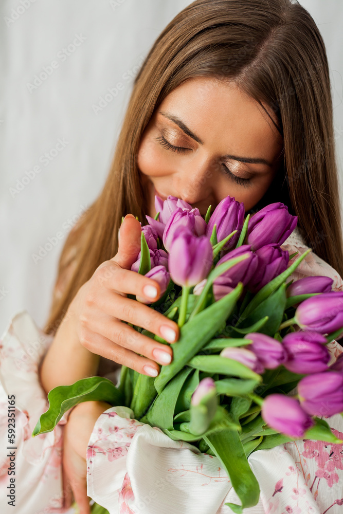 Portrait of sexy beautiful young woman with long hair. Model with a bouquet of lilac tulips on white. Spring. Holidays. Portrait of sexy beautiful young woman with long hair. Model with a bouquet of lilac tulips on white. Spring. Holidays.