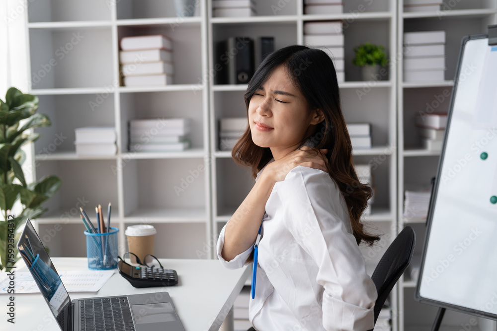 Asian businesswomen suffer from shoulder pain from working too much in an office.