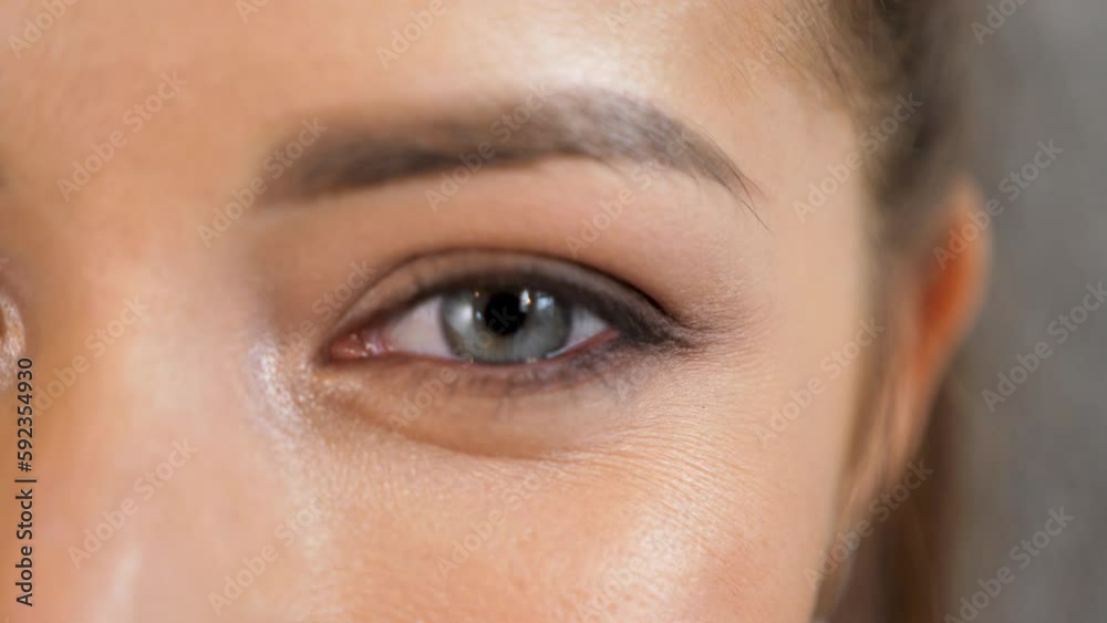 Closeup Beautiful Woman eye. Young blue eyed girl, macro shoot. Female face winking and looking at camera