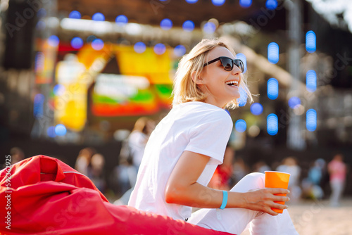 Fotografie Smiling young woman drinking beer and relaxing at music festival
