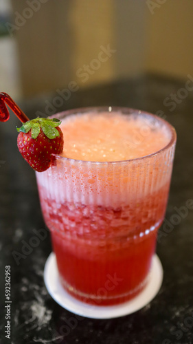 A glass of strawberry juice at the table with a fancy straw.
