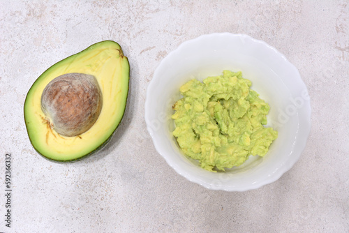 Avocado and smashed avocado in white bowl isolated, close-up