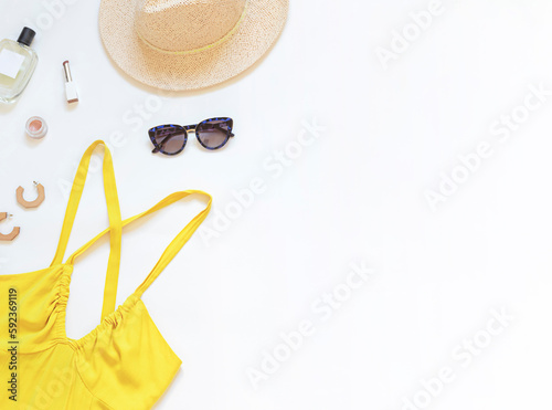 Summer yellow dress with straw hat and sunglasses on the white background. Top view. Copy space 