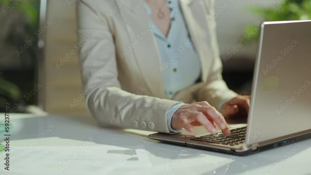 Closeup on woman worker in a light business suit in green office with laptop. Closeup on woman worker in a light business suit in green office with laptop.