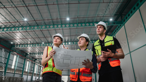 Team engineers workers planning and talking in empty warehouse to design the arrangement of product shelves and organize strategy about new manufacturing.