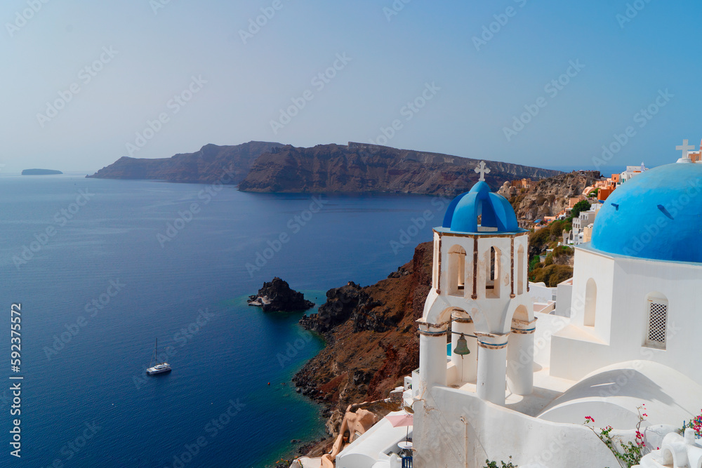 Fototapeta premium traditional greek village Oia of Santorini, with blue domes and white walls against sea and caldera, Greece