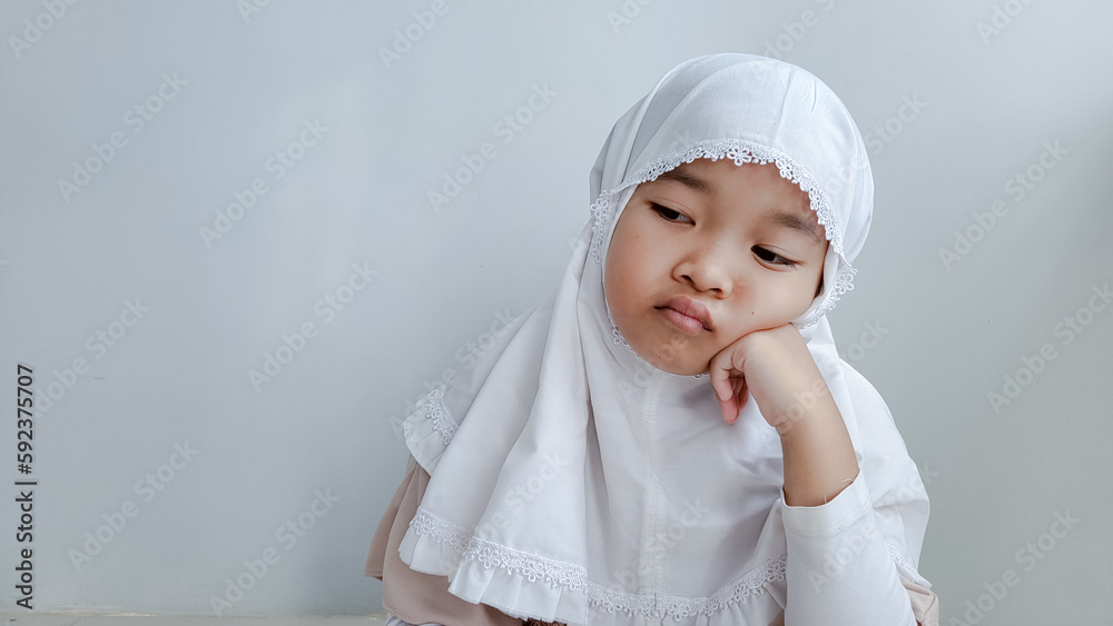 annoyed face of asian girl while thinking and wearing hijab on gray background. Islamic moment concept. annoyed face of asian girl while thinking and wearing hijab on gray background. Islamic moment concept.