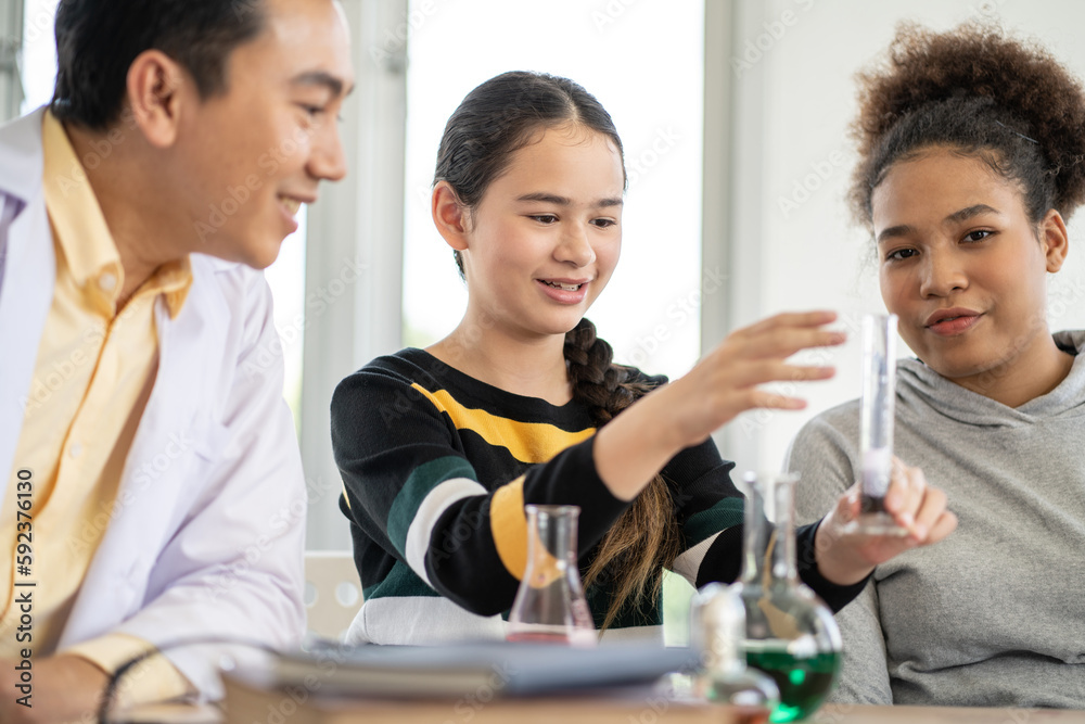 Students in science class doing chemical experiment in laboratory. Girl mixing chemistry in test tube. learning and education concept. Teacher watching and supporting kids Students in science class doing chemical experiment in laboratory. Girl mixing chemistry in test tube. learning and education concept. Teacher watching and supporting kids