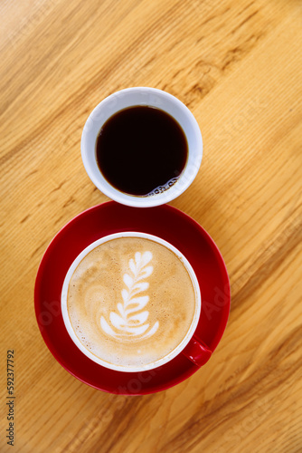 Coffee in a red cup with milk and latte art and coffee in a white cup on a table