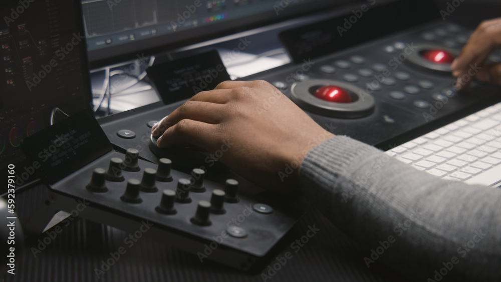 Hands close up of African American video editor working by color grading control panel in studio with modern design. Colorist makes colour correction for movie post production. Professional equipment. Hands close up of African American video editor working by color grading control panel in studio with modern design. Colorist makes colour correction for movie post production. Professional equipment.
