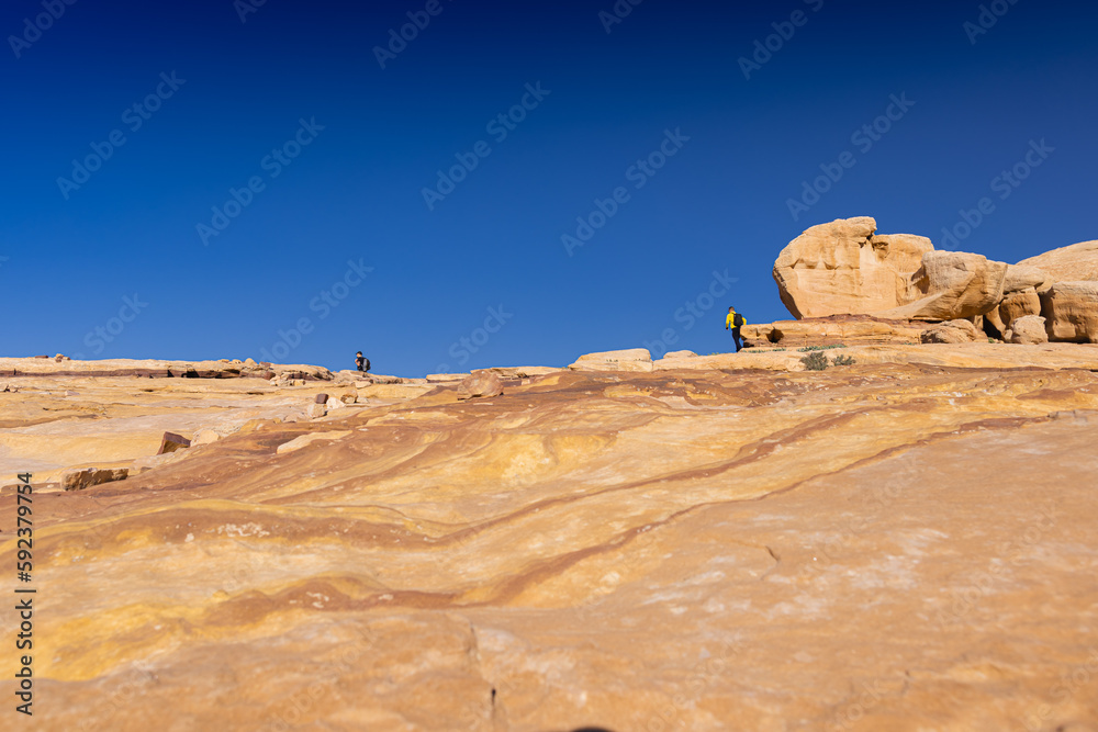 Petra w Jordanii. Widok na skalną pustynię na tle błękitnego, bezchmurnego nieba.  - obrazy, fototapety, plakaty 