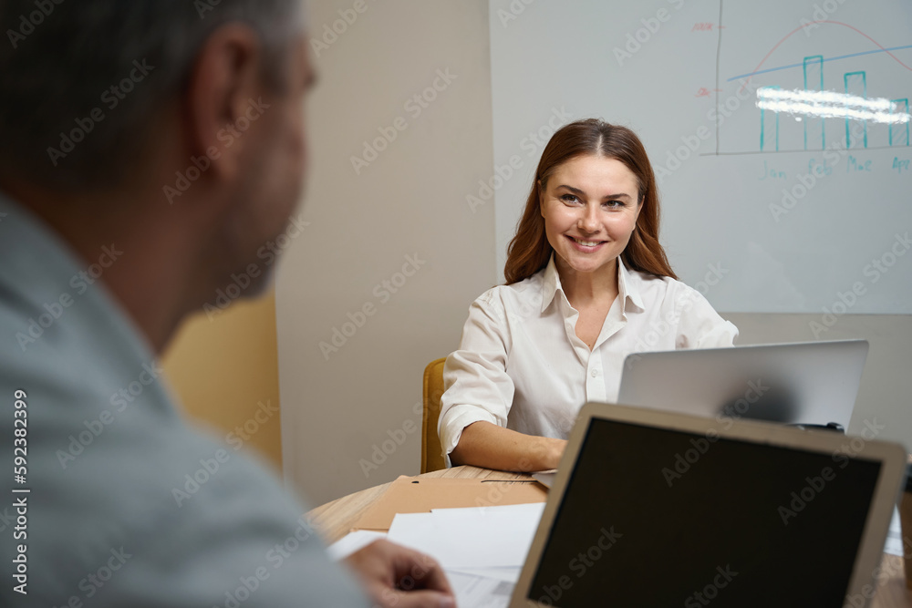 Smiling woman talking with employee in the office Smiling woman talking with employee in the office
