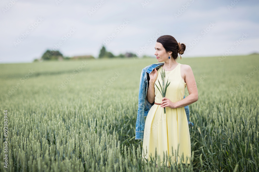 Lifestyle portrait of young stylish woman walking by wheat field