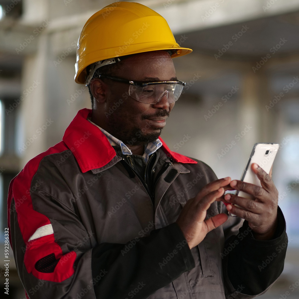 African american workman with smartphone at construction site African american workman with smartphone at construction site