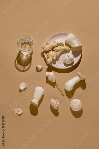 Wallpaper Mural Eringi mushrooms, glass of water, garlic and ginger on a plate on pastel beige background with sunlit. Fresh food concept suitable for vegans and vegetarians. Torontodigital.ca