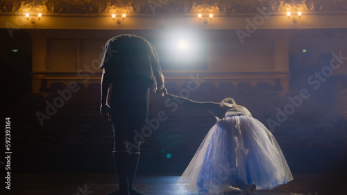 Φωτογραφία Ballet dancers bowing during choreography rehearsal on classic theater stage illuminated by spotlight