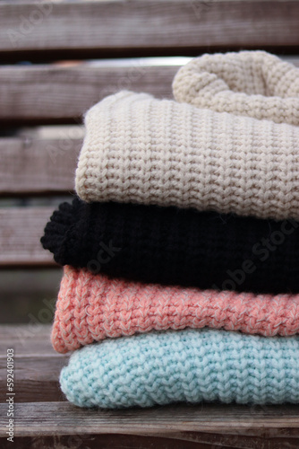 Stack of woolen sweaters folded on wooden background