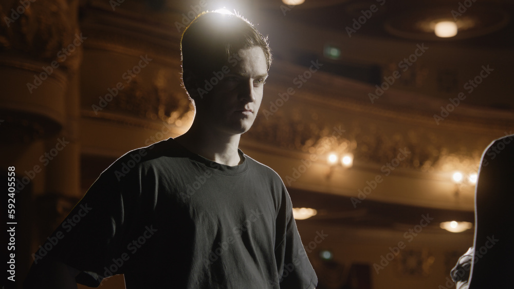 Concentrated ballet male dancer stands with ballerina on theater stage ...
