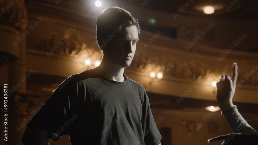 Concentrated ballet male dancer stands with ballerina on theater stage ...