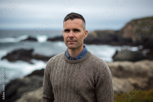 Portrait of a handsome man standing on the rocks by the ocean